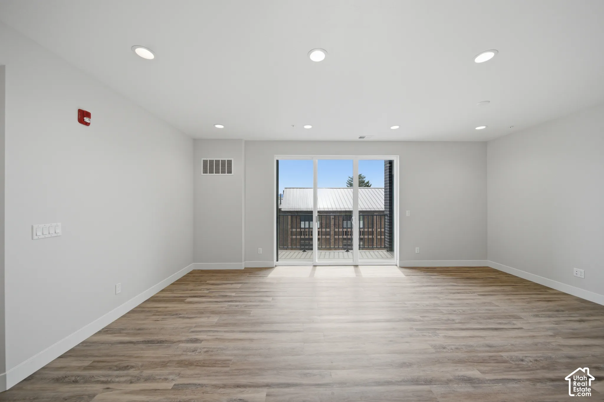 Spacious room featuring wood-finish flooring, recessed lighting, and white baseboards