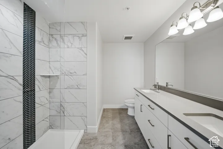 Contemporary bathroom featuring a spacious dual-sink vanity with white cabinetry, a large mirrored surface, and an overhead vanity light fixture