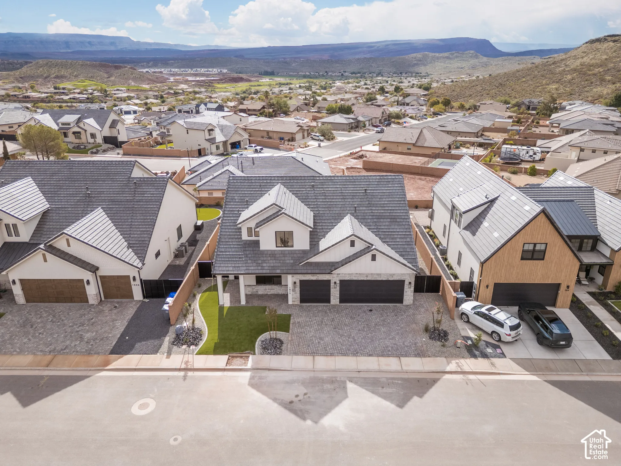 Two-story residence featuring a tile roof, stone and stucco exterior, three-car garage, and landscaped front yard