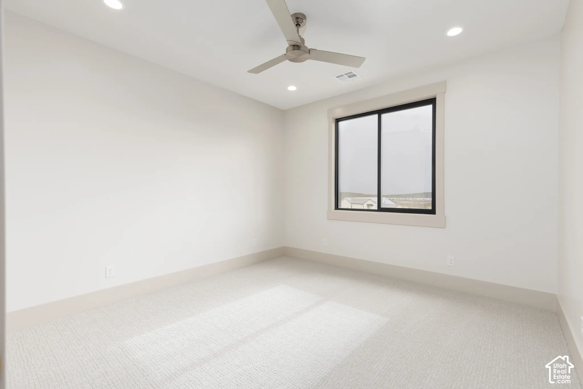 Neutral-toned interior space featuring light-colored wall-to-wall carpeting, recessed ceiling lighting, and a neutral-finish ceiling fan