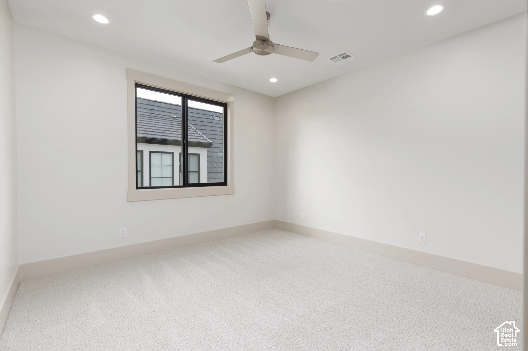 Neutral-toned interior room featuring wall-to-wall carpeting, recessed ceiling lighting, and a modern brushed-metal ceiling fan