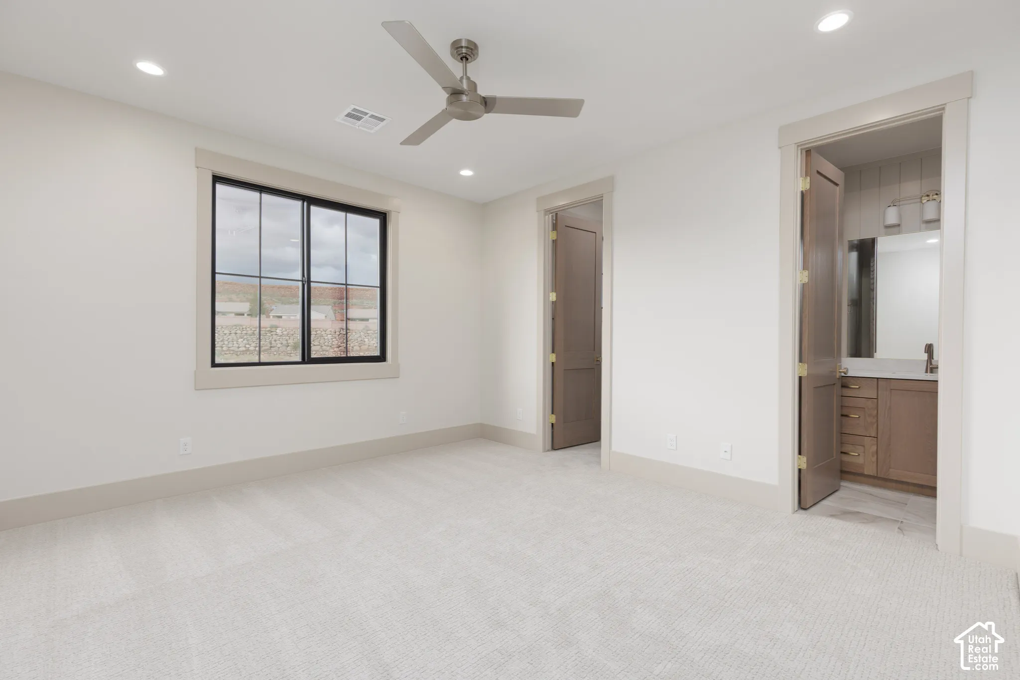 Neutral-toned wall-to-wall carpeting, recessed ceiling lighting, three-blade ceiling fan, multi-pane window with dark trim, and solid-core interior doors