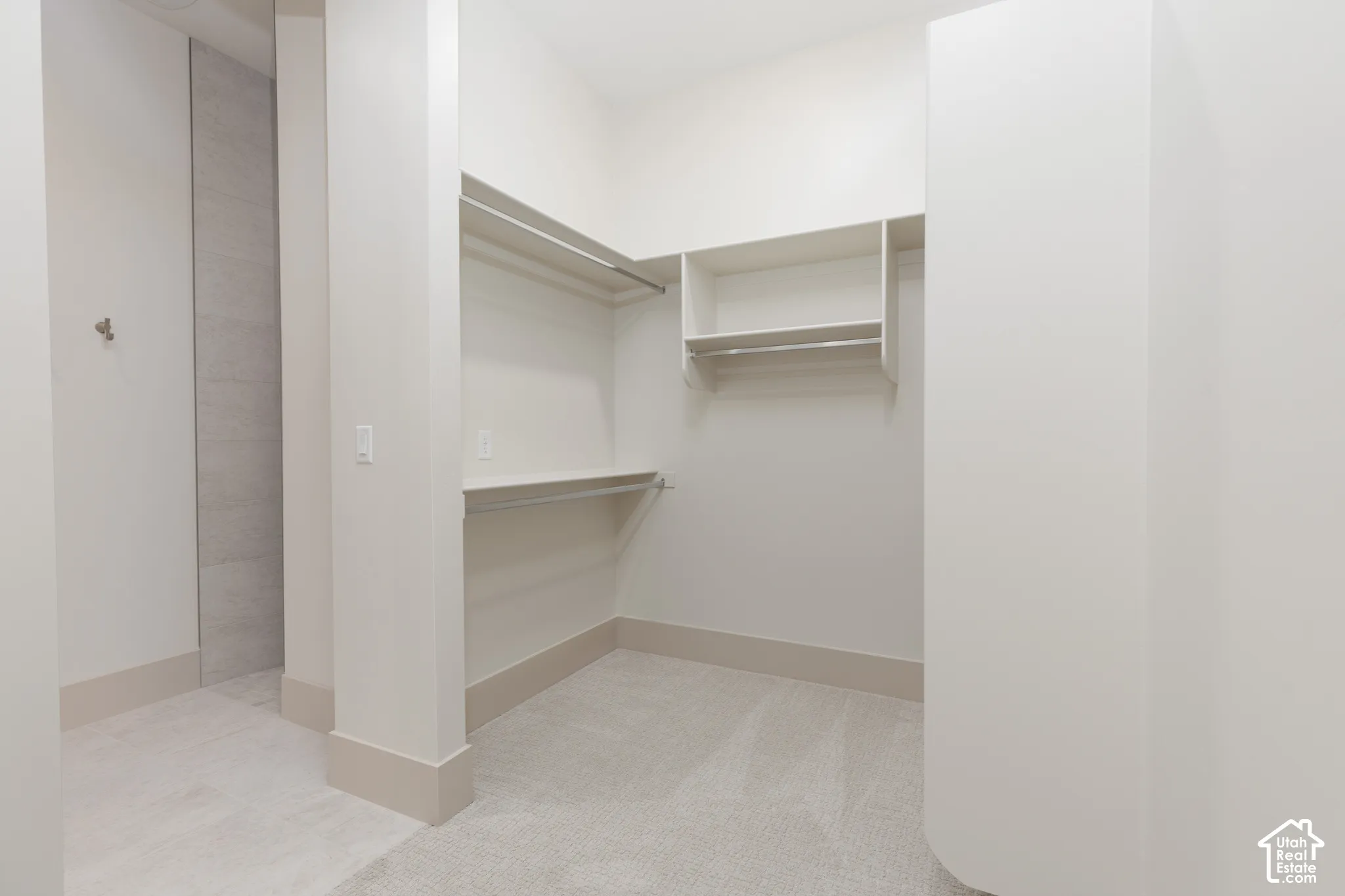 Walk-in storage area featuring custom built-in shelving, hanging rods, carpeted flooring, and neutral wall tones