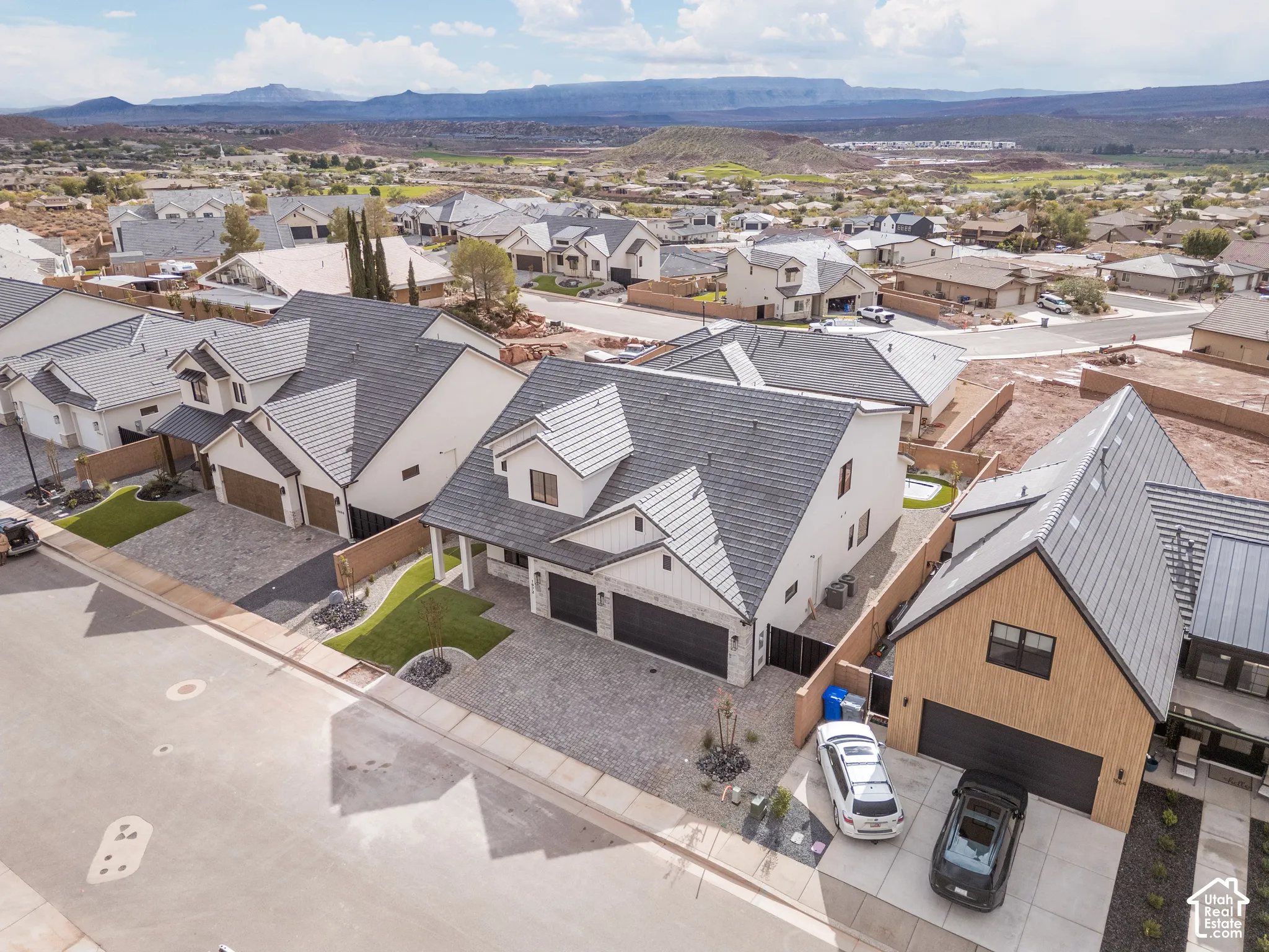 Two-story residence featuring a multi-gabled roofline, stone and stucco exterior, attached multi-car garage, and desert-inspired landscaping against a mountain backdrop