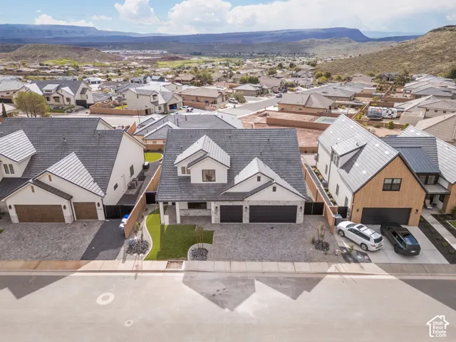 Two-story residence featuring a tile roof, stone and stucco exterior, three-car garage, and landscaped front yard
