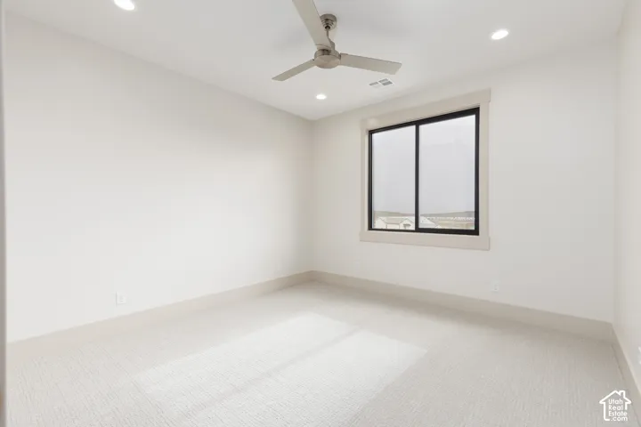 Neutral-toned interior space featuring light-colored wall-to-wall carpeting, recessed ceiling lighting, and a neutral-finish ceiling fan