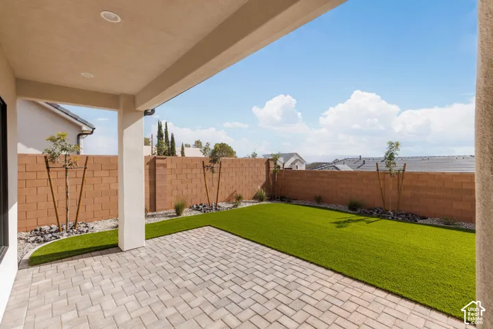 Covered patio with recessed lighting, stone paver flooring, synthetic turf lawn, and masonry perimeter wall