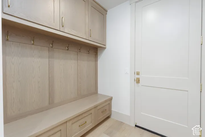 Built-in wood-finish cabinetry with overhead storage, integrated bench seating, lower storage drawers, and brass-tone hardware, featuring a solid-core door with matching brass-tone fixtures