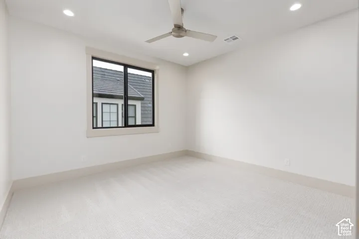 Neutral-toned interior room featuring wall-to-wall carpeting, recessed ceiling lighting, and a modern brushed-metal ceiling fan