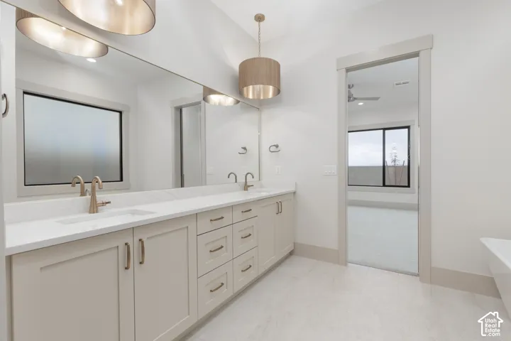 Double vanity with integrated sinks, expansive wall-to-wall mirror, neutral-toned cabinetry, satin-finish hardware, and pendant lighting