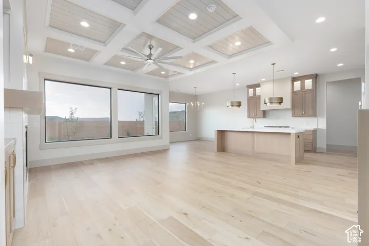 Coffered ceiling with wood-finish inlay, expansive windows, wood-finish flooring, island kitchen with custom cabinetry, and recessed lighting