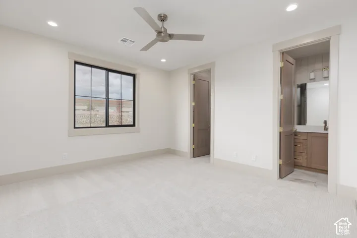 Neutral-toned wall-to-wall carpeting, recessed ceiling lighting, three-blade ceiling fan, multi-pane window with dark trim, and solid-core interior doors