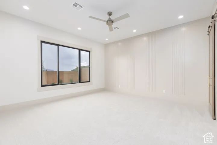 Room featuring wall molding, carpeted flooring, a ceiling fan, recessed lighting, and a sliding barn-style door