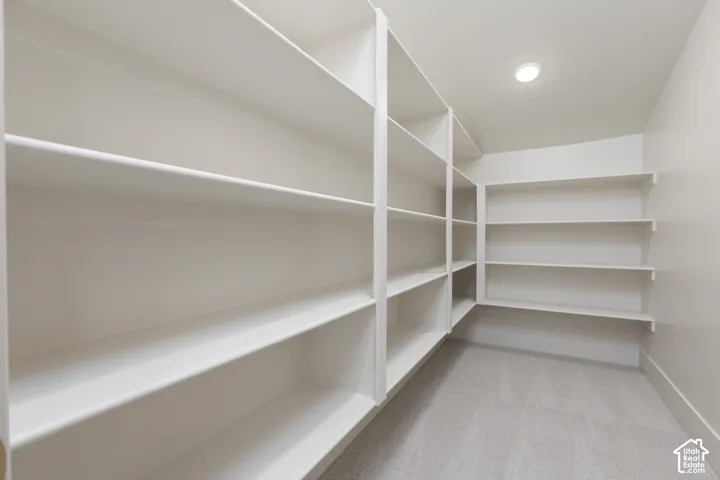 Walk-in storage space featuring multi-tier built-in shelving, recessed ceiling lighting, and wall-to-wall carpeting