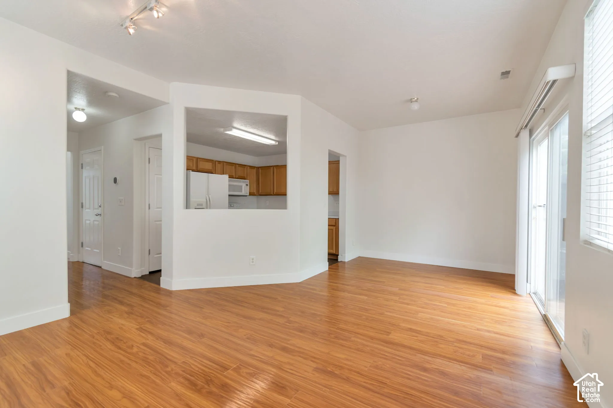 Open-concept interior featuring wood-finish flooring, a kitchen pass-through window, and sliding glass doors