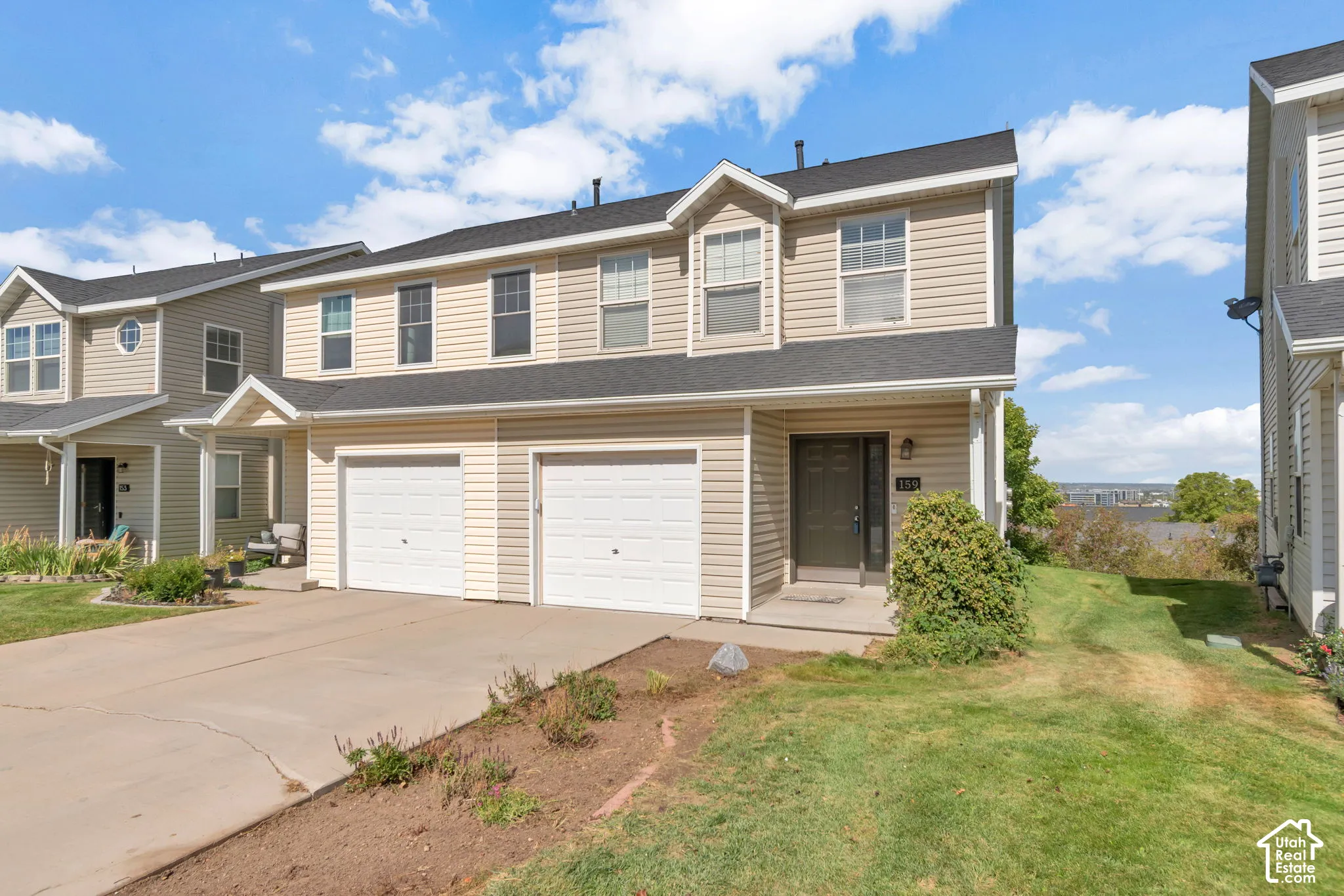 Two-story exterior featuring light-toned horizontal siding, a pitched roof, and two attached garage bays with paneled doors