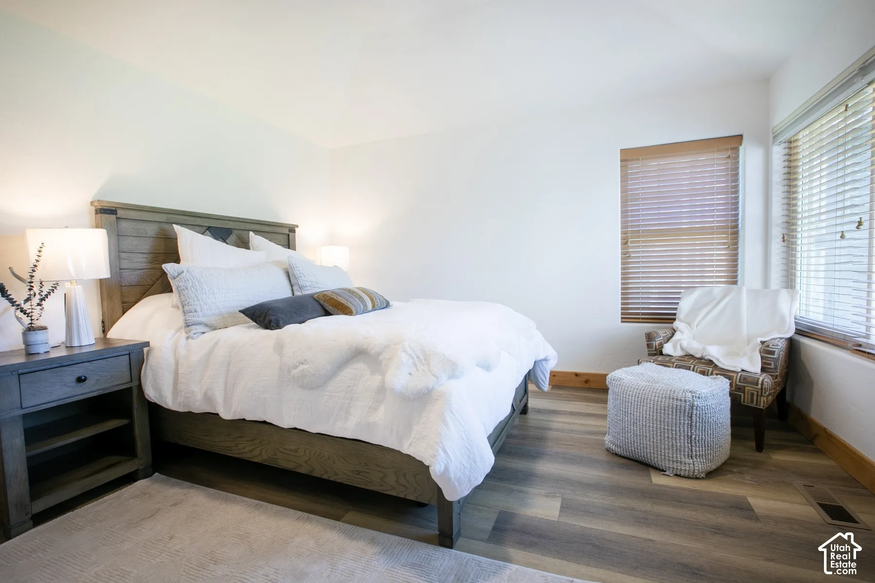 Vaulted ceiling, wood-finish flooring, and multiple windows featuring horizontal blinds