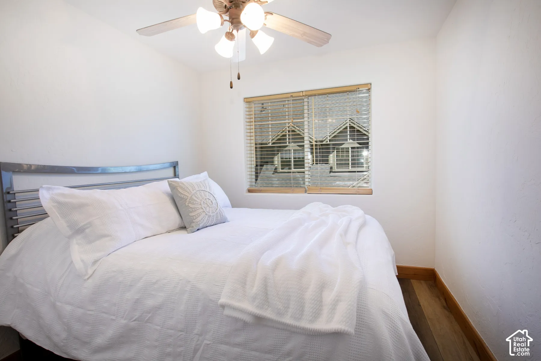 Interior room featuring wood-finish flooring, a ceiling fan with integrated lighting, and a window equipped with horizontal blinds