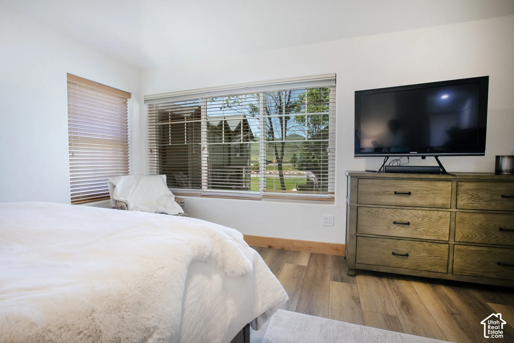 Wood-finish flooring, multi-pane windows with horizontal blinds, and neutral wall tones