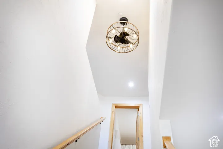Cage-style ceiling fixture with exposed bulbs, light-toned wood handrails, and smooth white walls