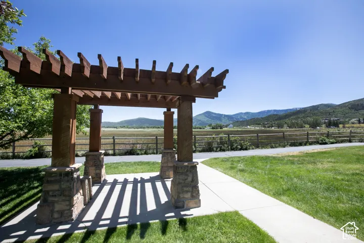 Wooden pergola featuring stone-column bases, concrete patio flooring, and mountainous backdrop