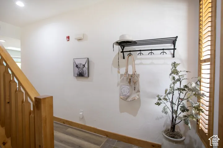 Entryway featuring a wall-mounted metal coat rack, wood-finish stair railing with matching trim, and wood-finish flooring