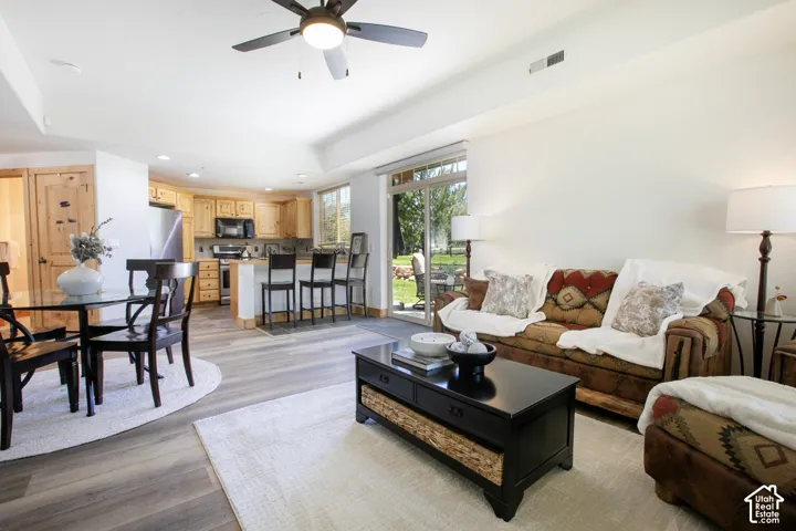 Open-concept main living area with wood-finish flooring, recessed lighting, ceiling fan, and sliding glass doors to the exterior