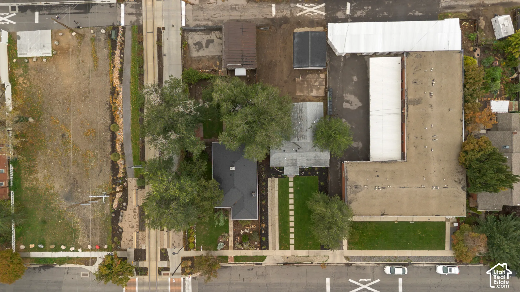 Aerial view of the parcel featuring mature trees, landscaped lawns, a paved driveway, and multiple structures