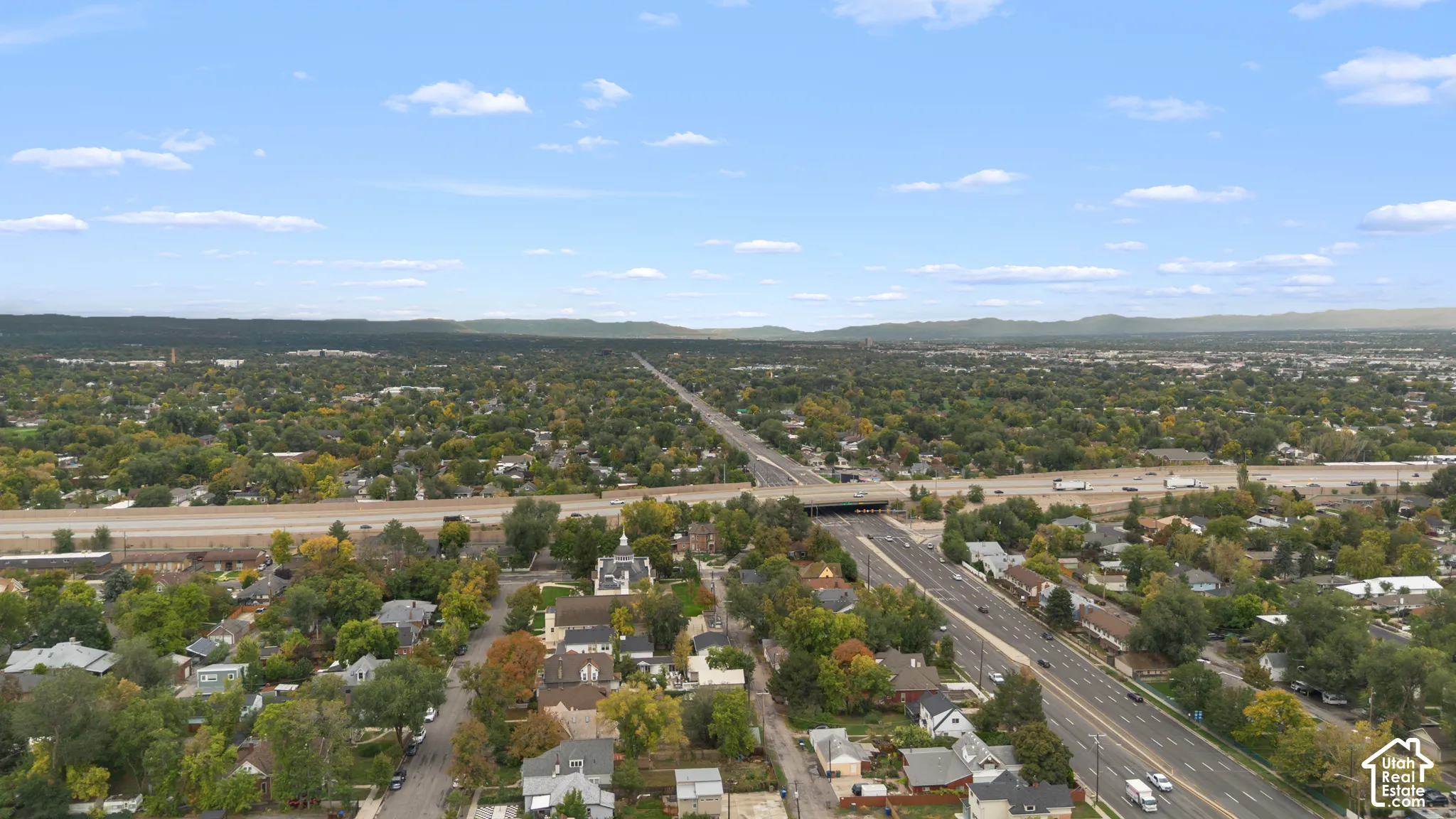 Aerial perspective featuring an established neighborhood with mature trees and expansive mountain silhouettes