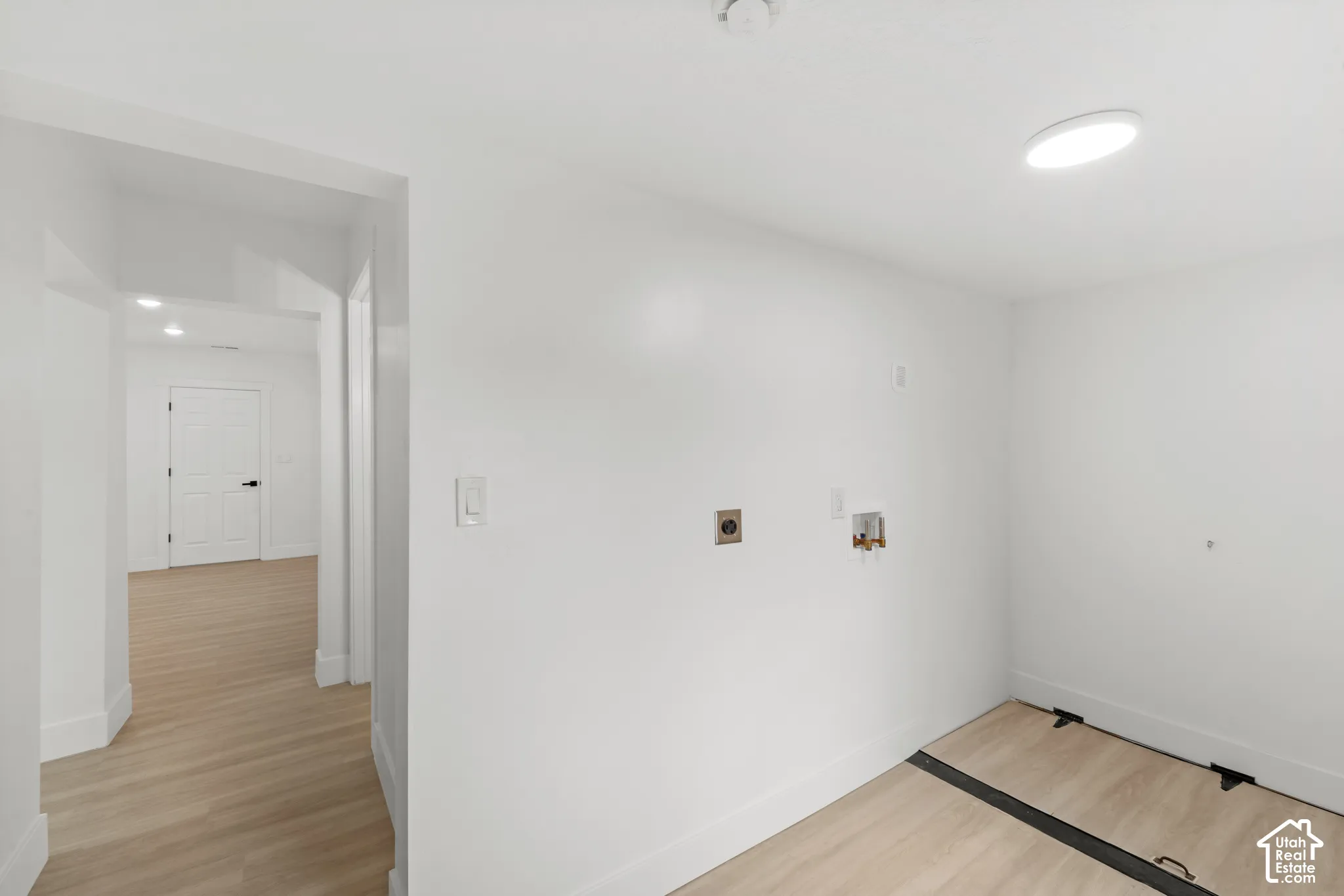 Utility area featuring washer and dryer hookups, flush-mount circular lighting, and wood-finish flooring