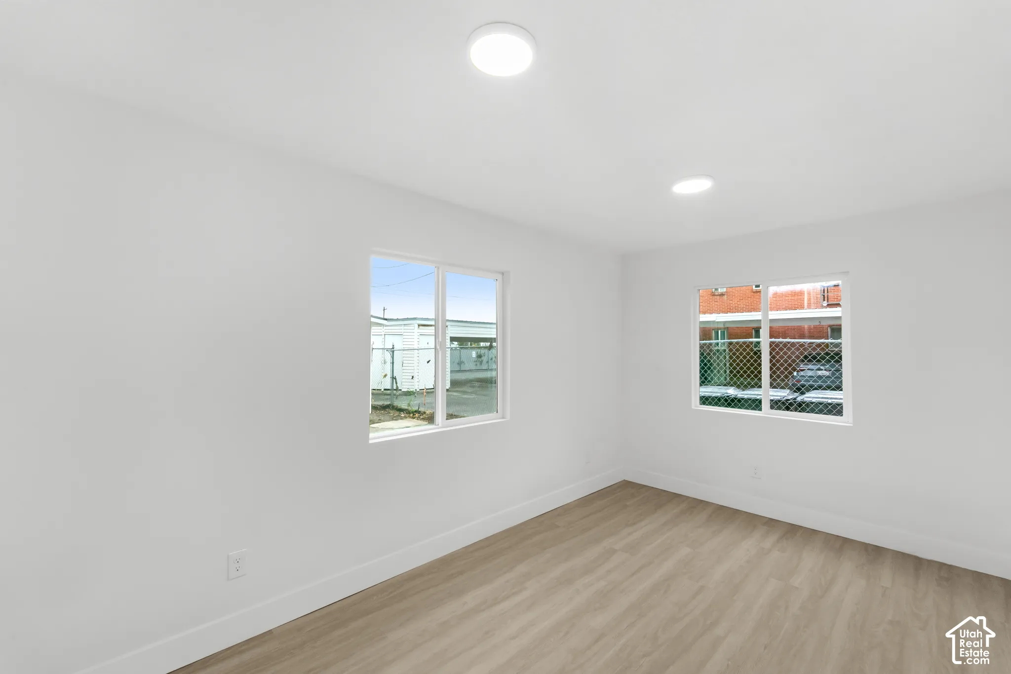 Interior space featuring wood-finish flooring, two dual-pane vinyl windows, and recessed ceiling lighting
