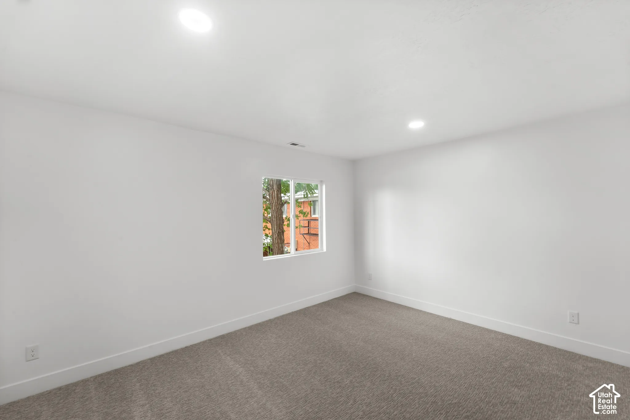 Interior room featuring neutral-toned carpeting, crisp white wall finishes, and recessed lighting
