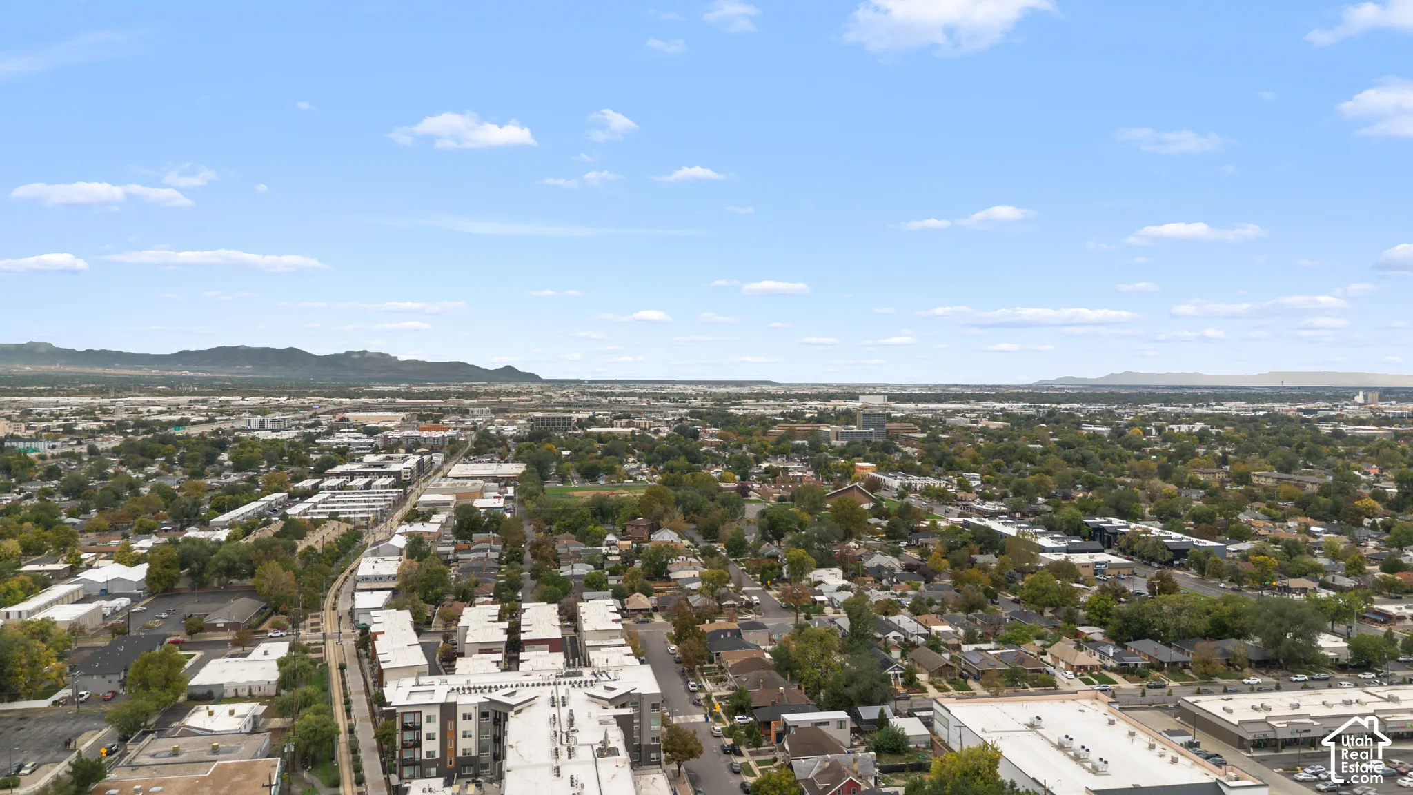 Aerial perspective showcasing a sprawling urban landscape with prominent mountain ranges on the horizon
