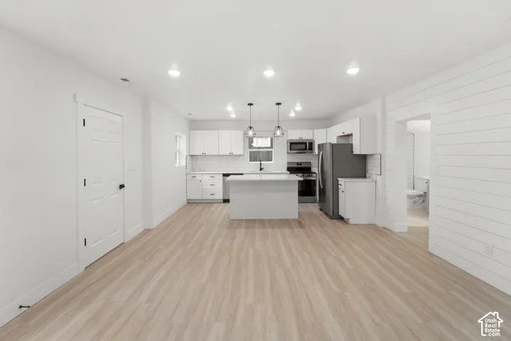 Kitchen featuring white cabinetry, a center island, wood-finish flooring, shiplap wall accents, and recessed ceiling lighting