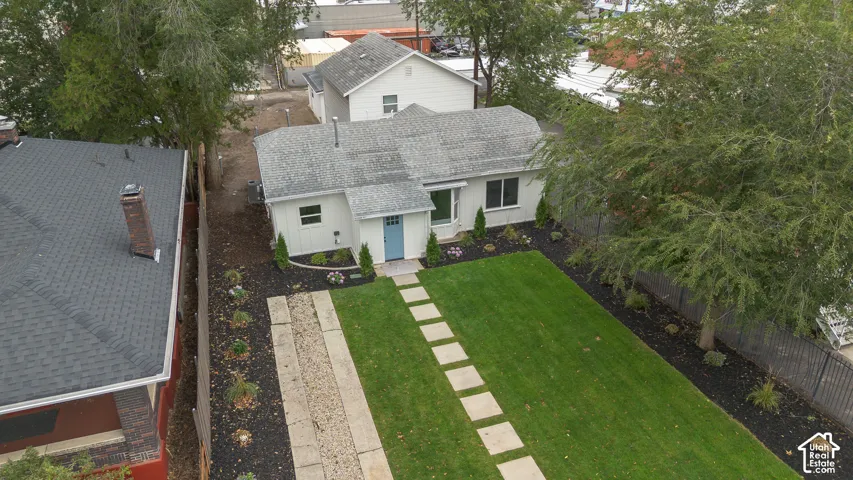 Single-story exterior featuring a light-toned facade, manicured lawn, stone paver walkway, and mature trees
