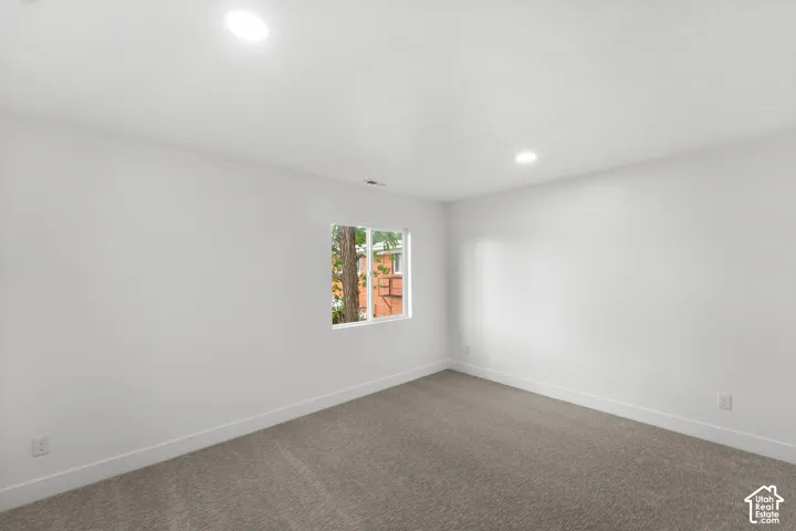 Interior room featuring neutral-toned carpeting, crisp white wall finishes, and recessed lighting