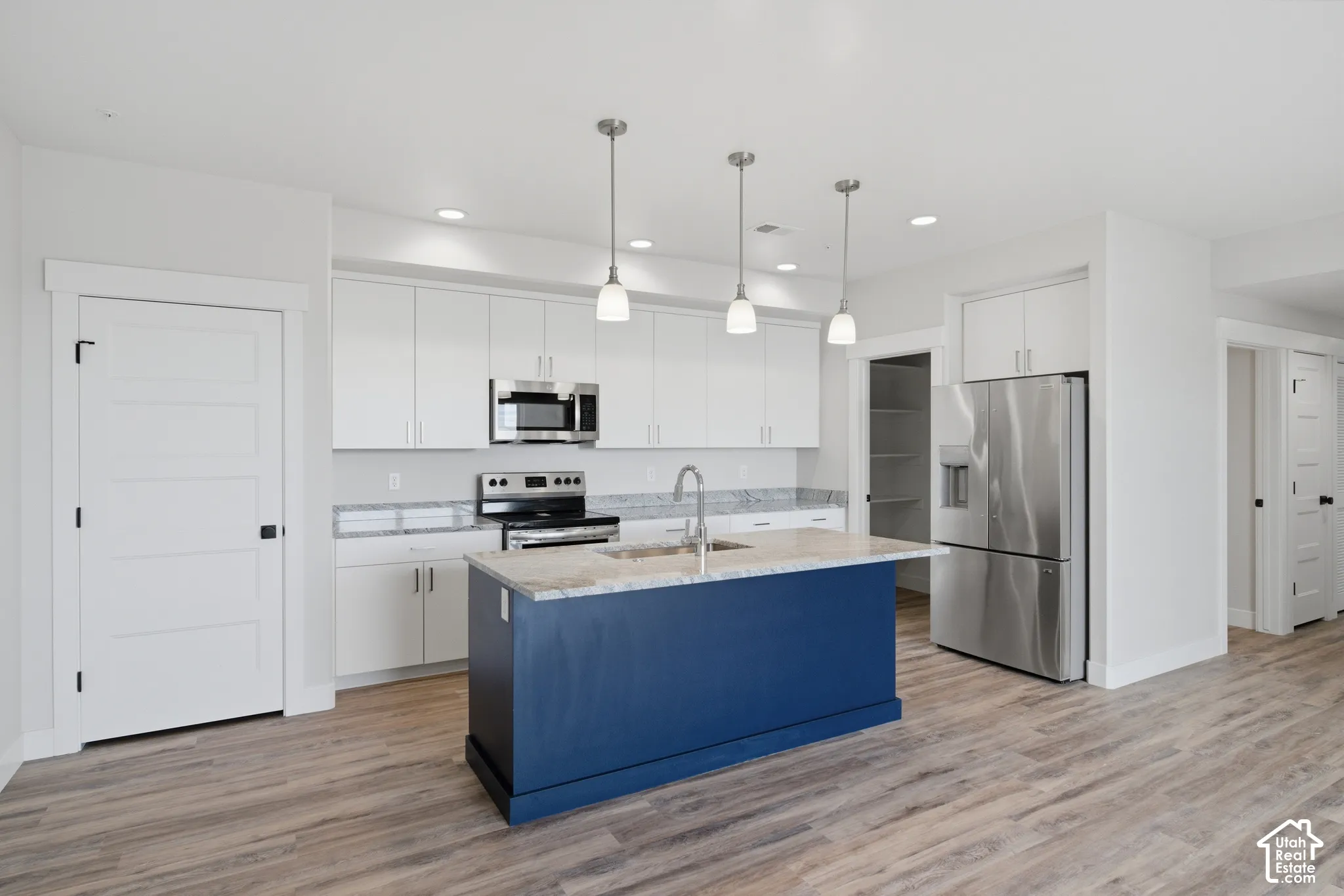 Kitchen featuring a navy-blue island with an integrated sink and pendant lighting