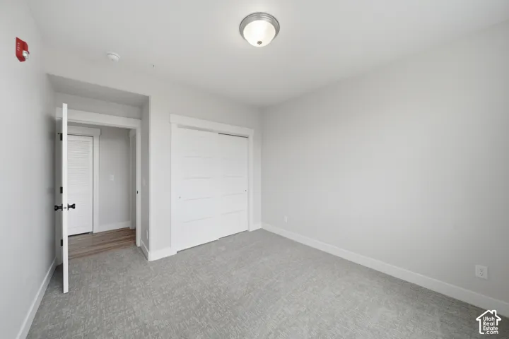 Neutral-toned room featuring a flush-mount ceiling light, patterned carpet flooring, and a sliding door closet