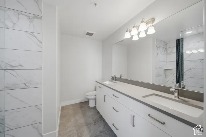 Spacious bathroom featuring a dual vanity with undermount sinks, stone countertops, and ample storage cabinetry