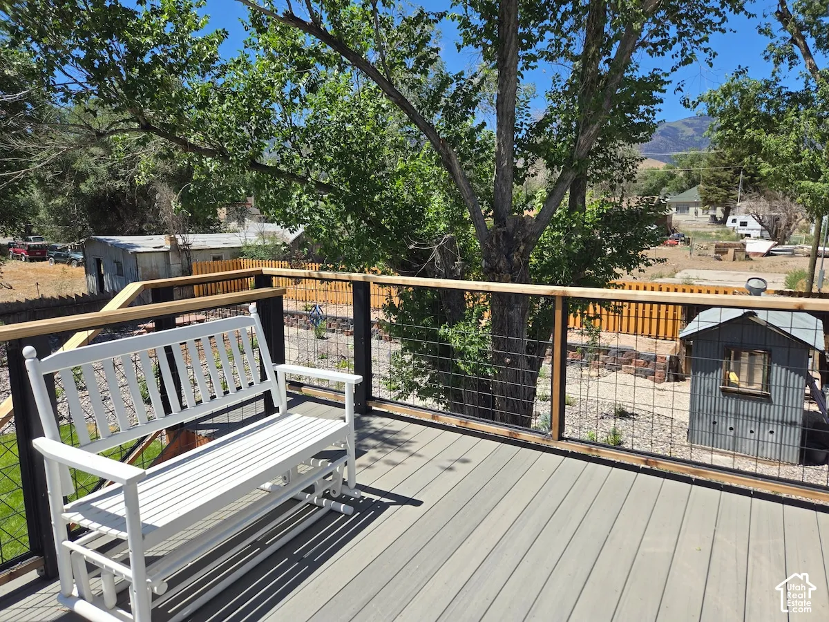 Elevated deck featuring composite wood-finish decking, wire-grid railing with wood-top handrails, and a mountainous backdrop
