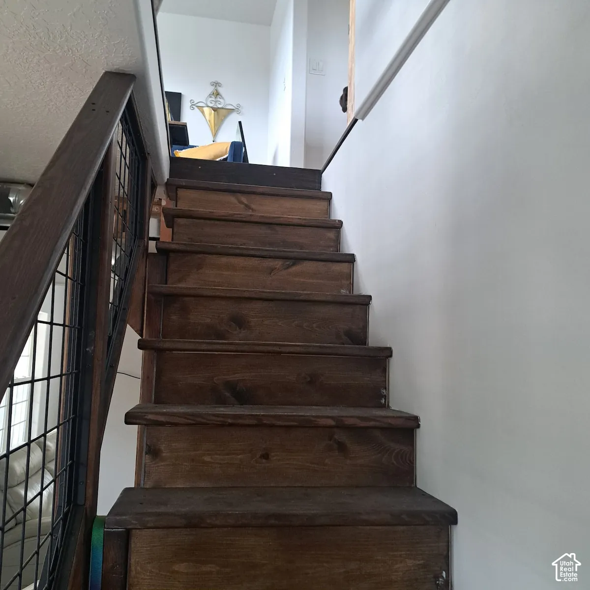 Staircase featuring dark-stained wood treads and a metal wire mesh railing system with a wood handrail