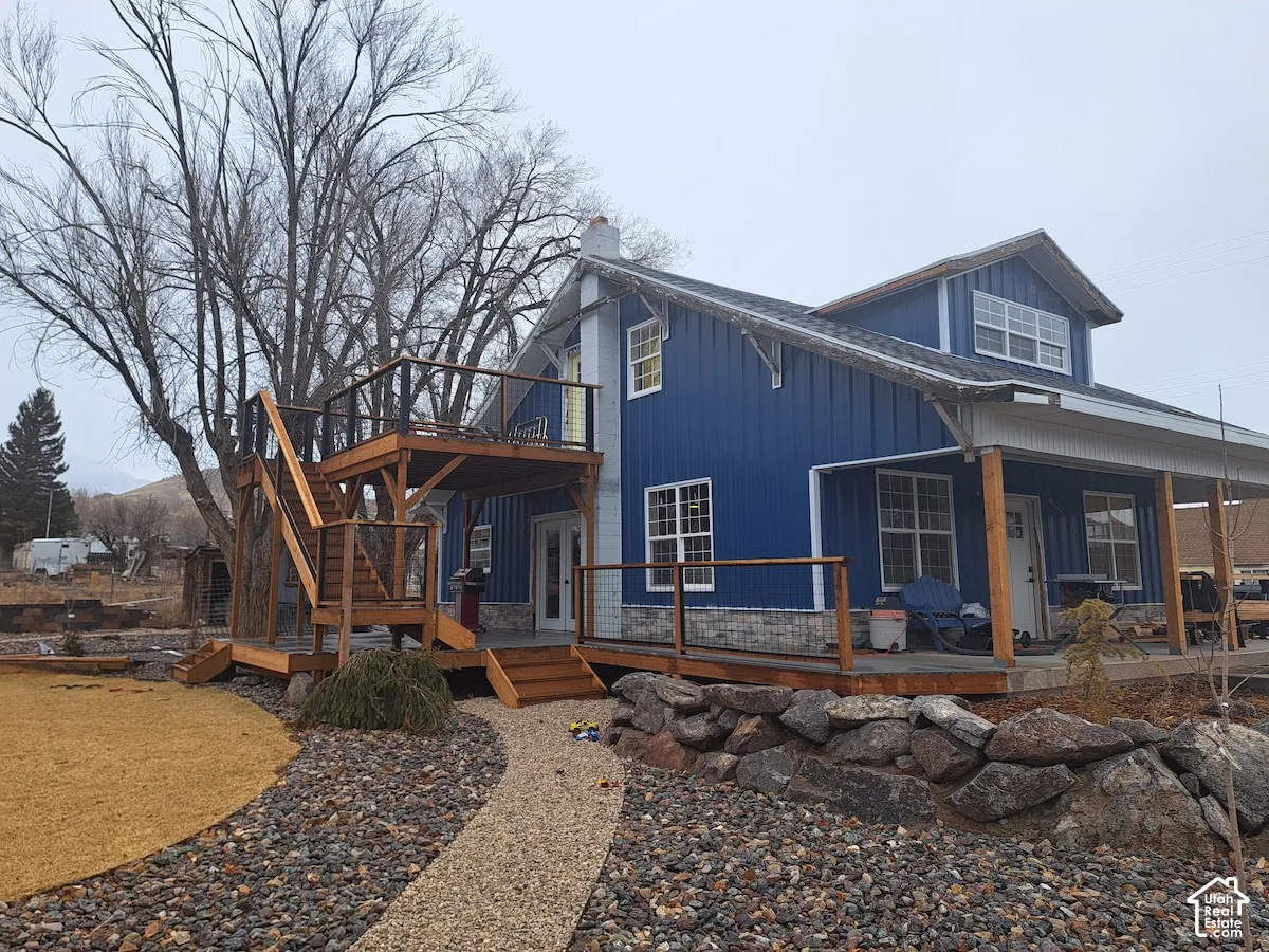 Vertical blue metal siding exterior featuring a stone veneer foundation, multi-level wood deck, metal stair railing, and a covered porch