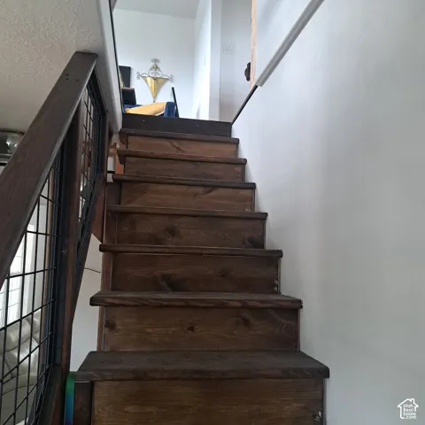 Staircase featuring dark-stained wood treads and a metal wire mesh railing system with a wood handrail