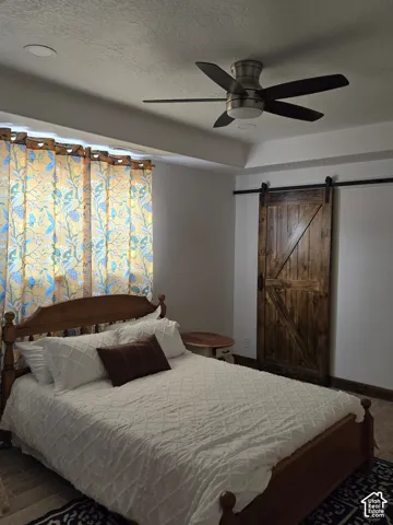 Room featuring a stained-wood sliding barn door, recessed ceiling lighting, and a five-blade ceiling fan with a brushed metal finish