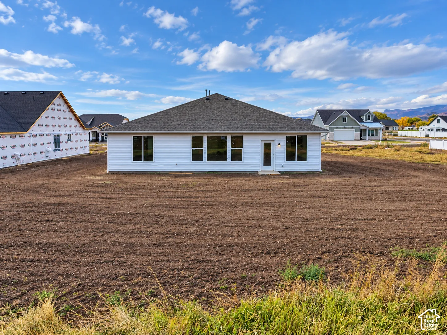 Single-story residence featuring white horizontal siding, a hipped roof, multi-pane windows, and a rear exterior door
