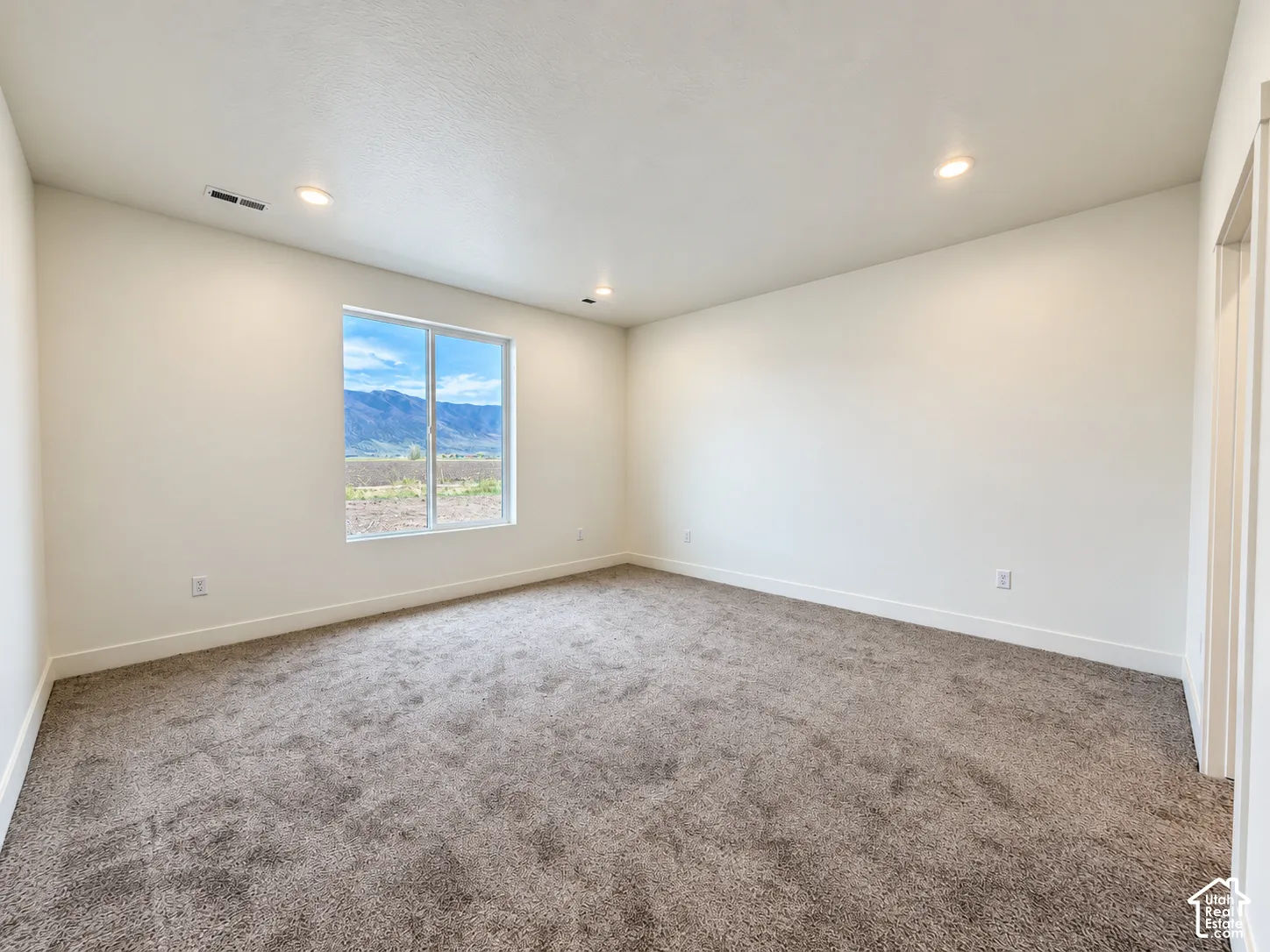 Interior room featuring neutral wall paint, wall-to-wall carpeting, recessed ceiling lighting, and a single-pane window with mountain scenery
