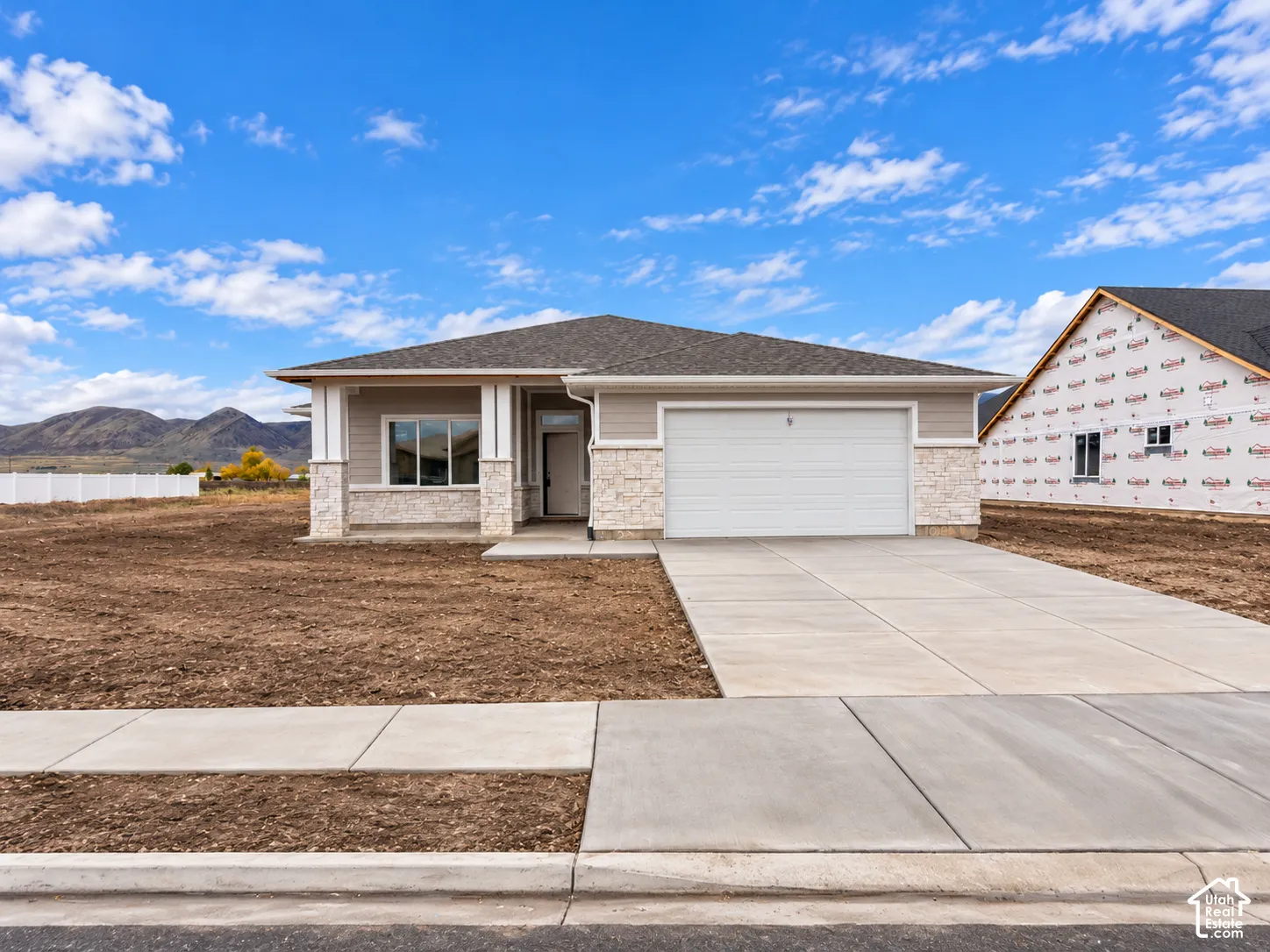 Single-level residence featuring a stone and siding exterior, a hip roof, a concrete driveway, and a covered entryway