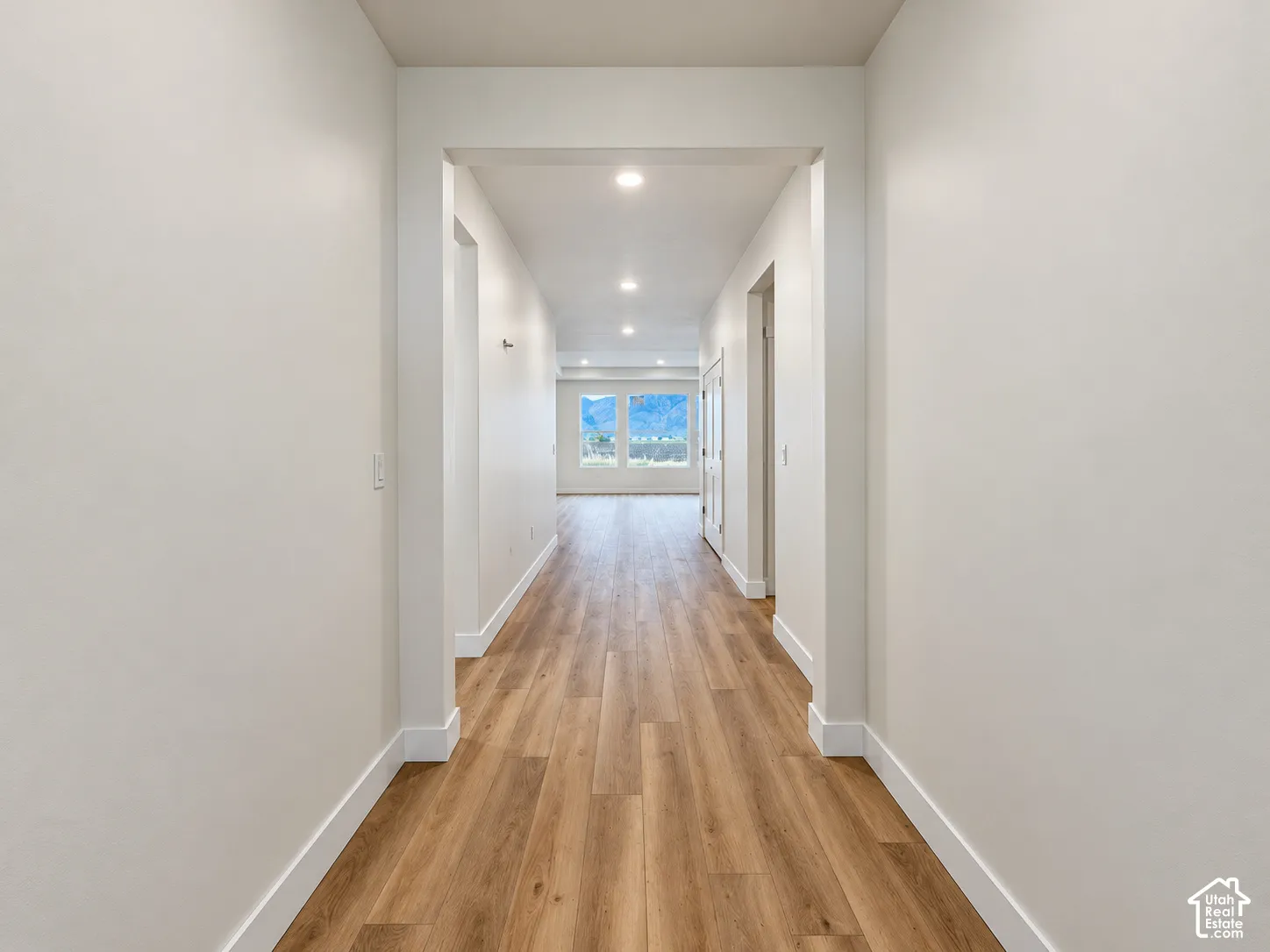 Hallway featuring wood-finish flooring, neutral wall tones, recessed lighting, and expansive windows with mountain scenery