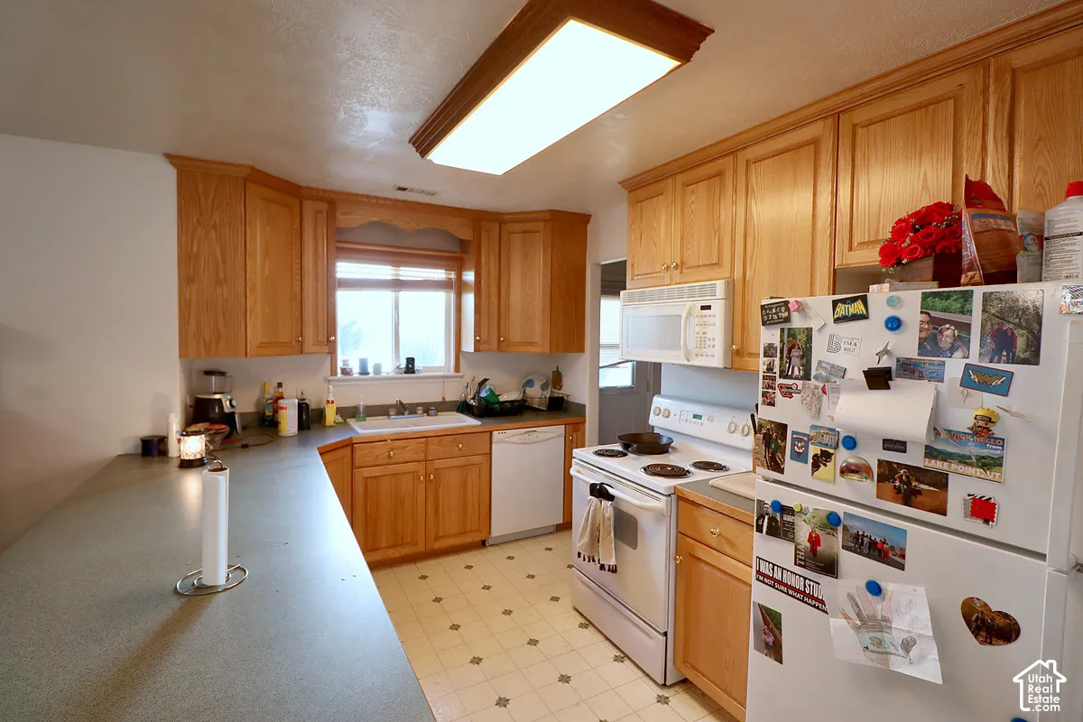 Kitchen featuring wood cabinetry, solid-surface countertops, built-in dishwasher, over-the-range microwave, and recessed ceiling lighting