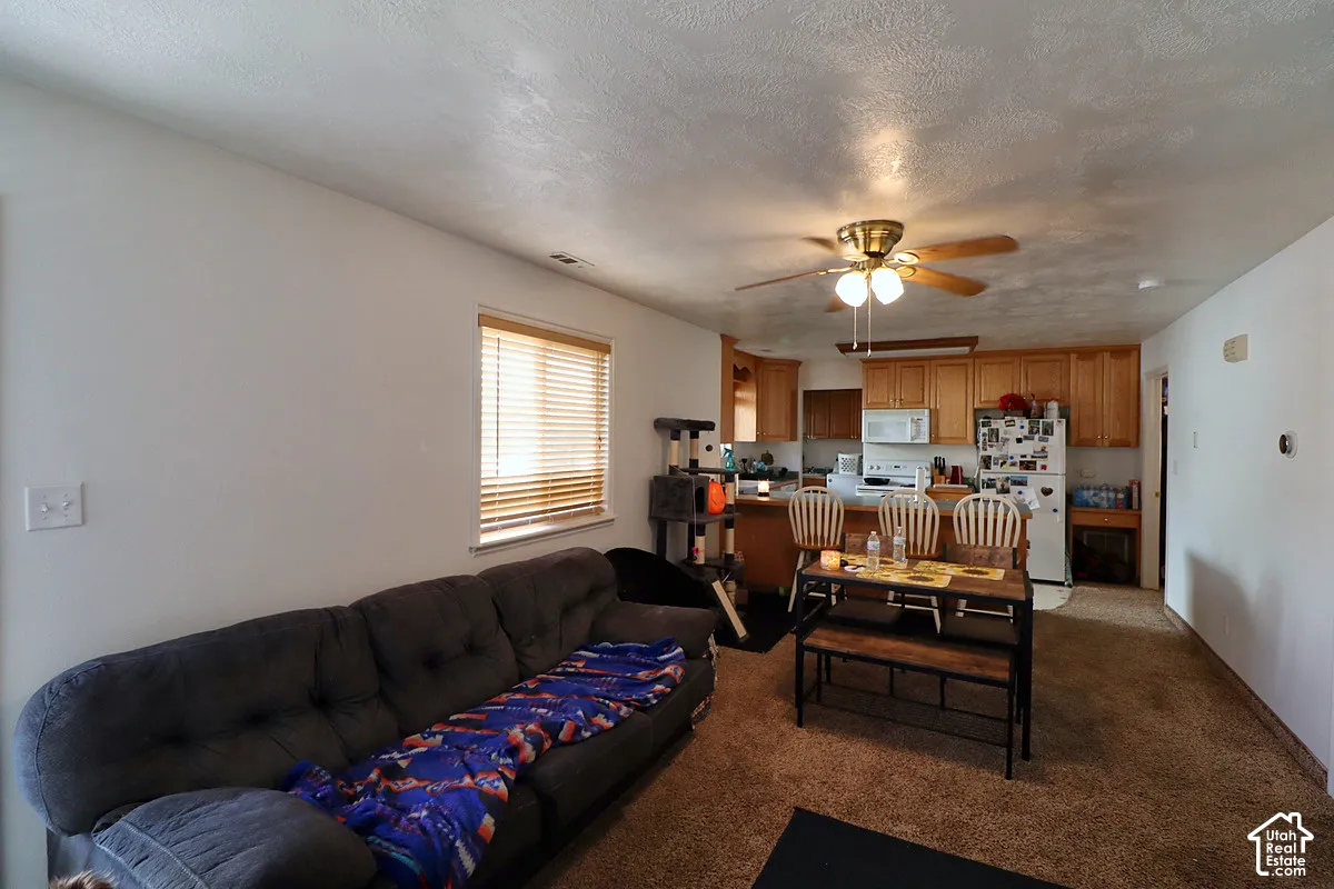 Kitchen featuring wood cabinetry, an integrated breakfast bar, and a ceiling fan with integrated light fixture